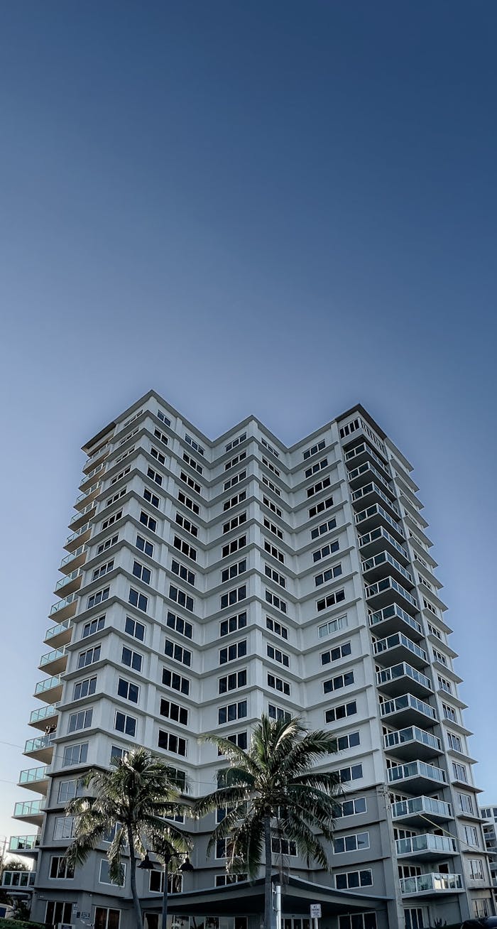 Low-angle view of a tall condominium building under a clear blue sky.